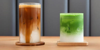Comparaison côte à côte : un latte glacé au café à gauche et un latte glacé au matcha vert à droite, posés sur une table en bois