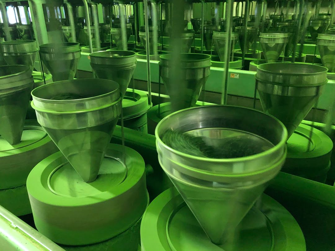 Rangées de meules de pierre traditionnelles broyant lentement le tencha en poudre de matcha dans une fabrique japonaise