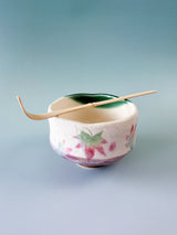 Chashaku en bambou posé en travers d'un bol à matcha chawan japonais décoré de feuilles d'érable
